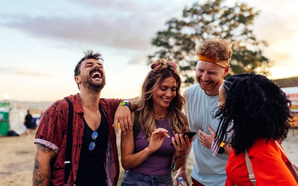 Two young couples laughing together at an outdoor concert