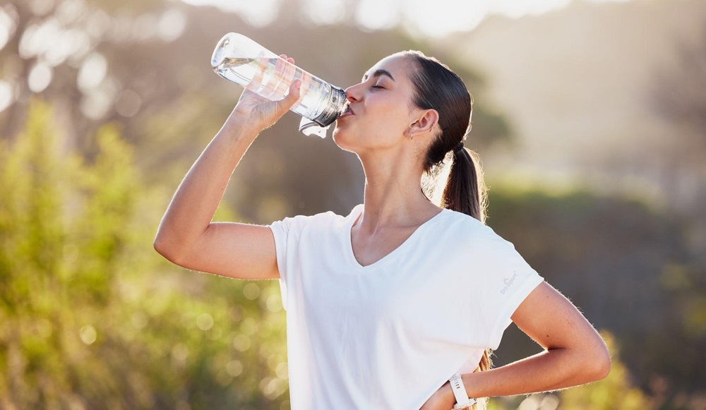 Woman on a hike drinking water from a reusable water bottle