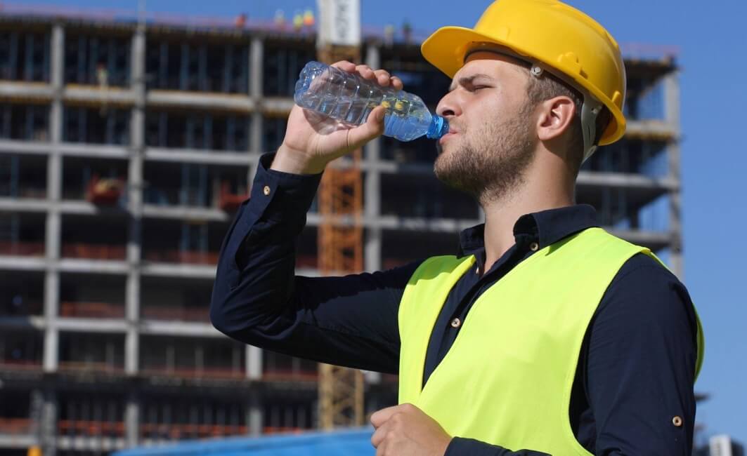 Construction worker drinking water outside on a hot day