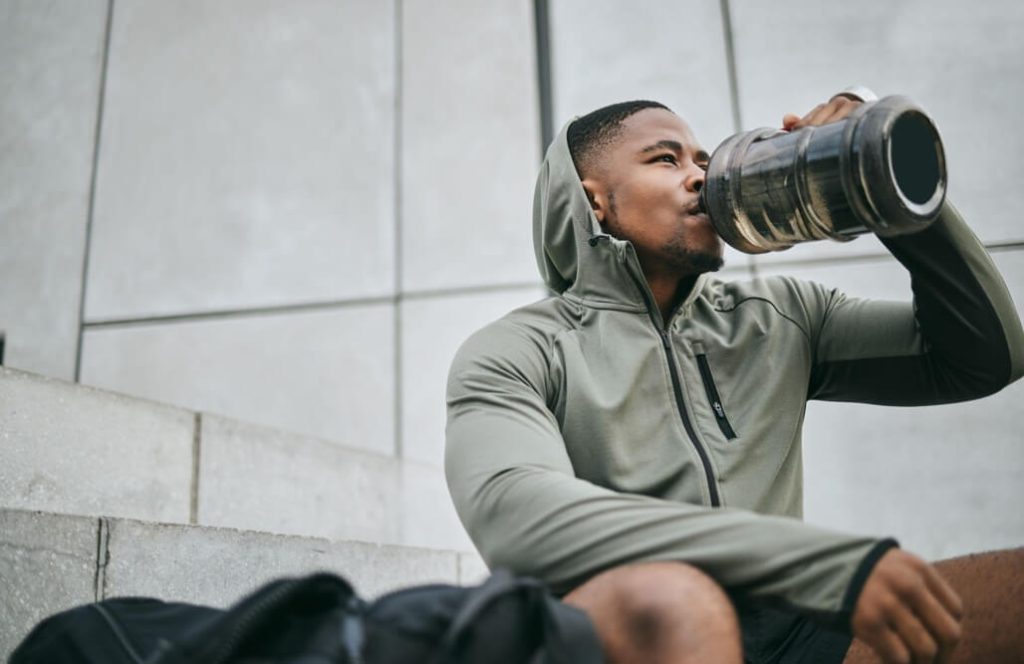 Man drinking water from a large reusable bottle after training
