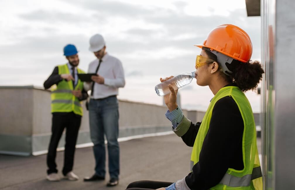 Young female construction worker drinking cold water on a break