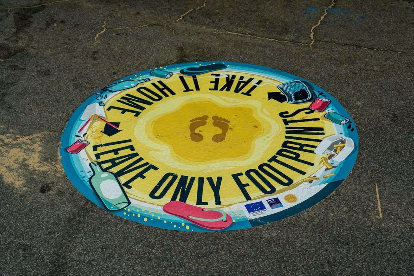 Sign on a sidewalk reading Take It Home, Leave Only Footprints