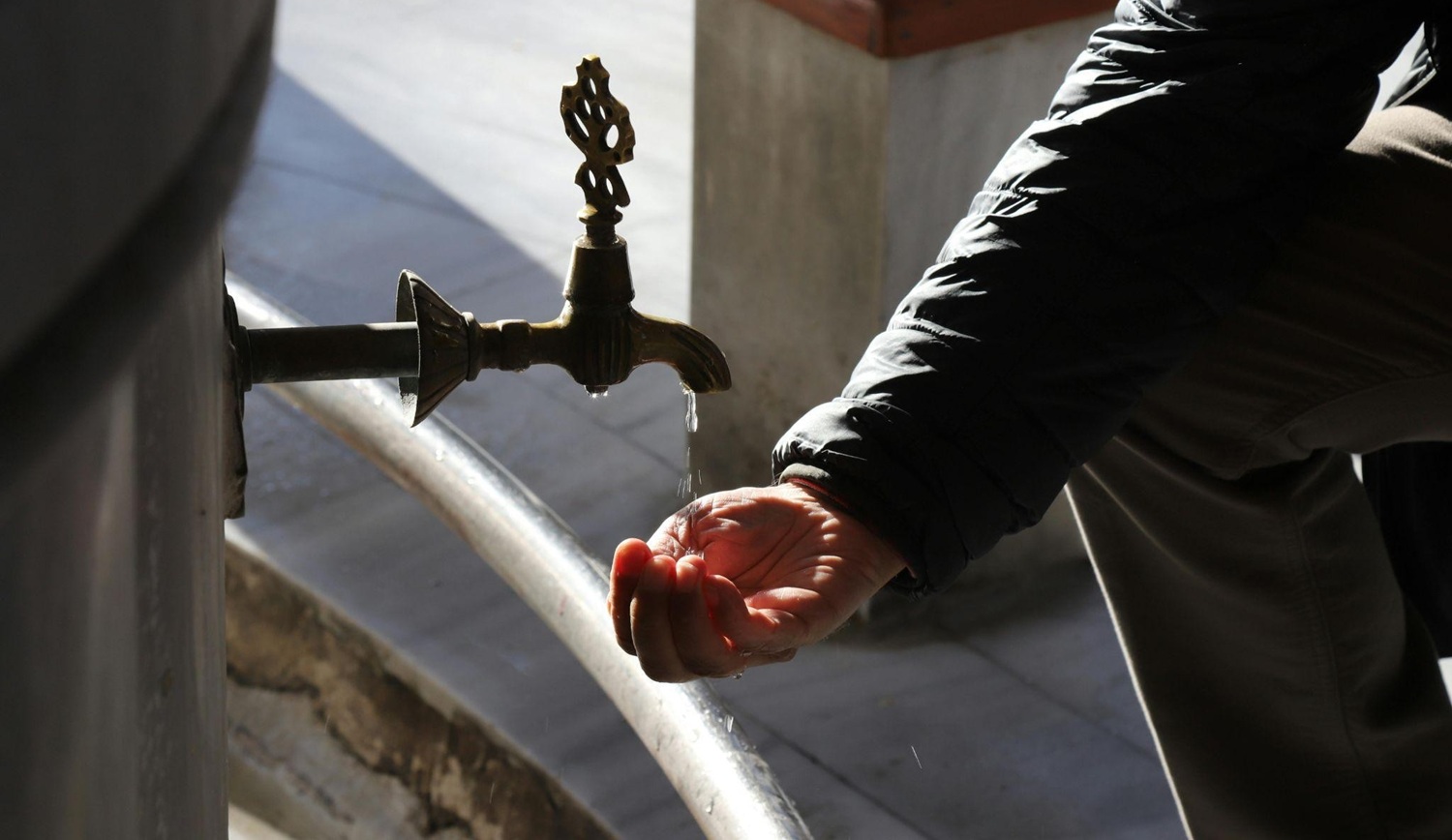 hand catching drips of water from an outdoor tap